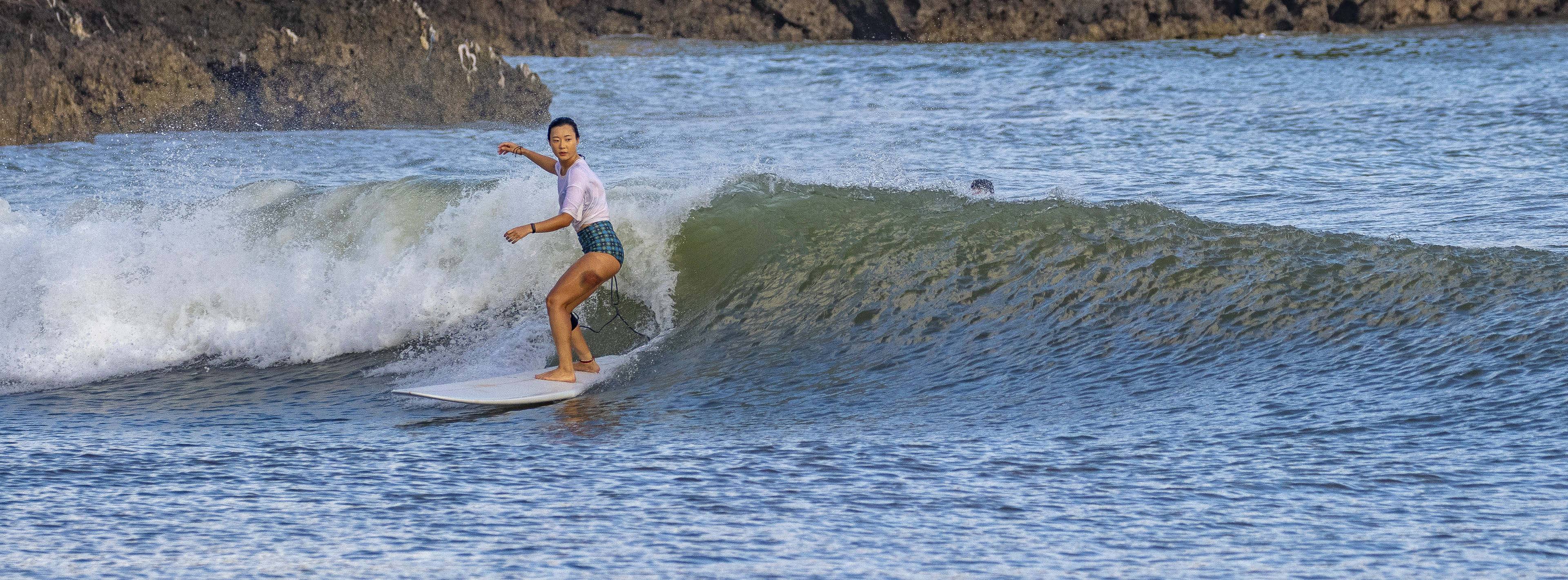 A surfer riding a wave at Pantai Muaya.