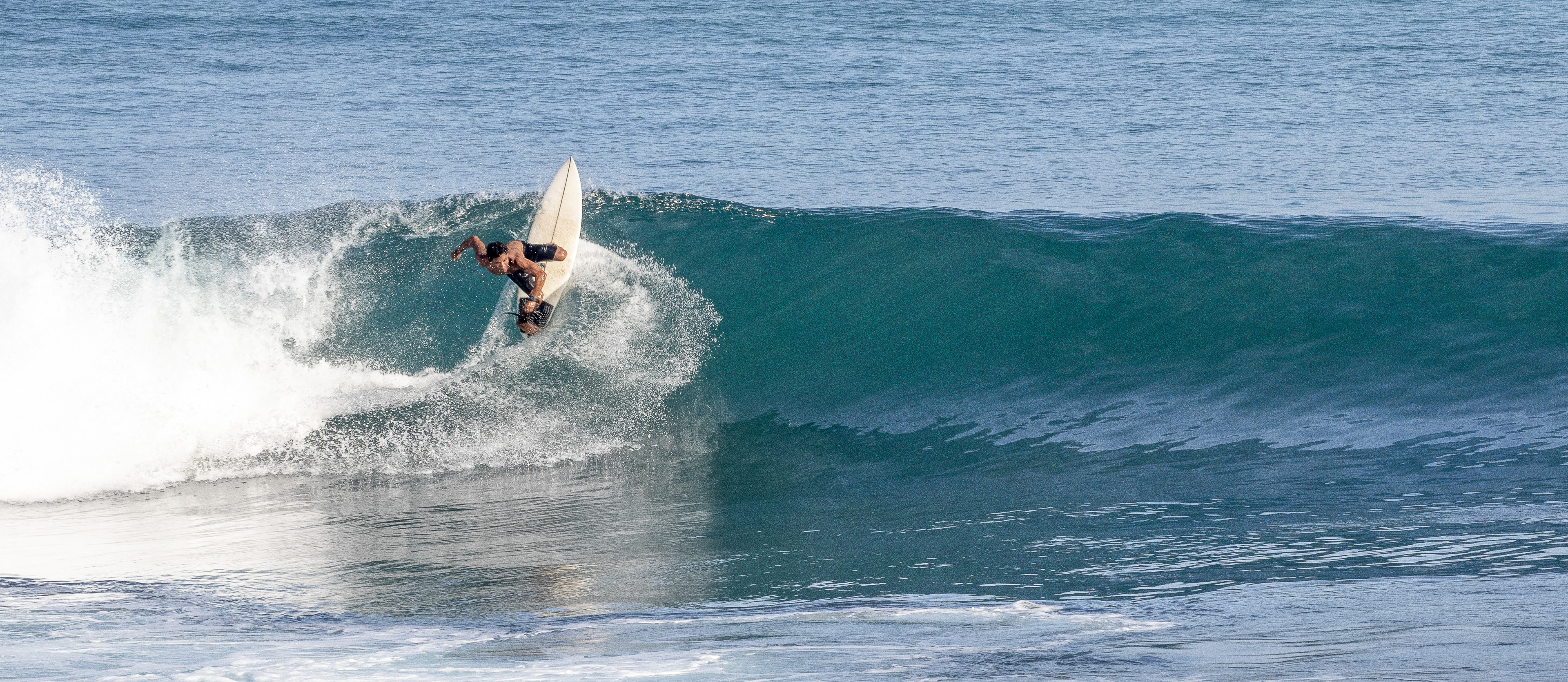 Surfer doing a backside top turn on a wave.